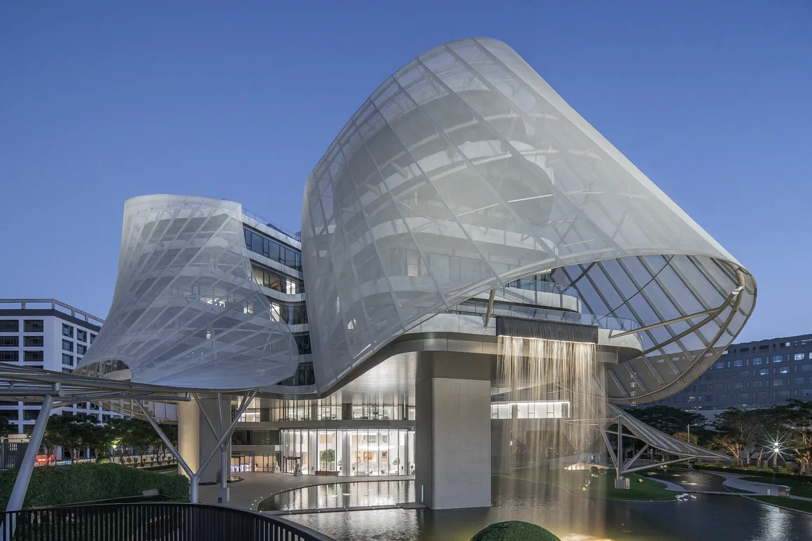 The built Xinhee Design Center at dusk: translucent PTFE membrane shells over the office arms, Xiamen.
